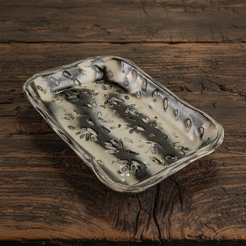 Rectangular ceramic dish with textured surface on a beige and brown background